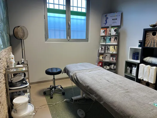 Sala trattamenti dello studio di Foligno: lettino con telo grigio, sgabello regolabile e mensole con prodotti per fisioterapia e massoterapia