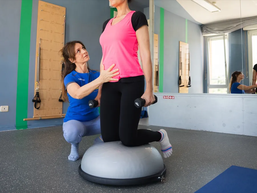 Anna Chiara Ferri assiste una paziente in equilibrio su BOSU con manubri, esercizio di rieducazione posturale nello studio di Spoleto