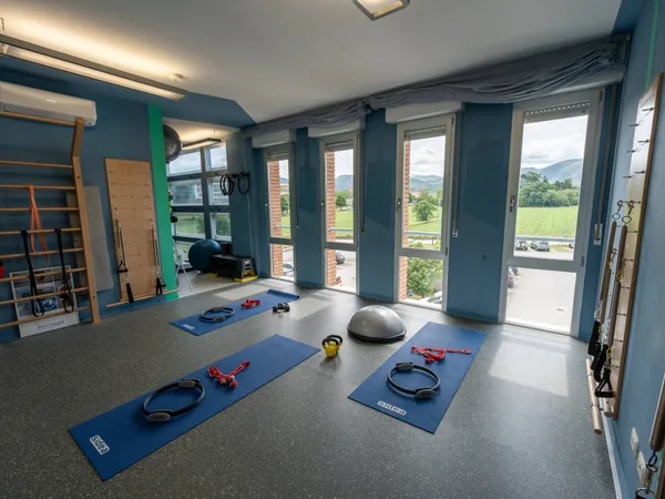 Sala apparecchiata per una lezione di gruppo nello studio di Spoleto con tappetini, magic circle, kettlebell e half-ball davanti alle vetrate sulle colline umbre